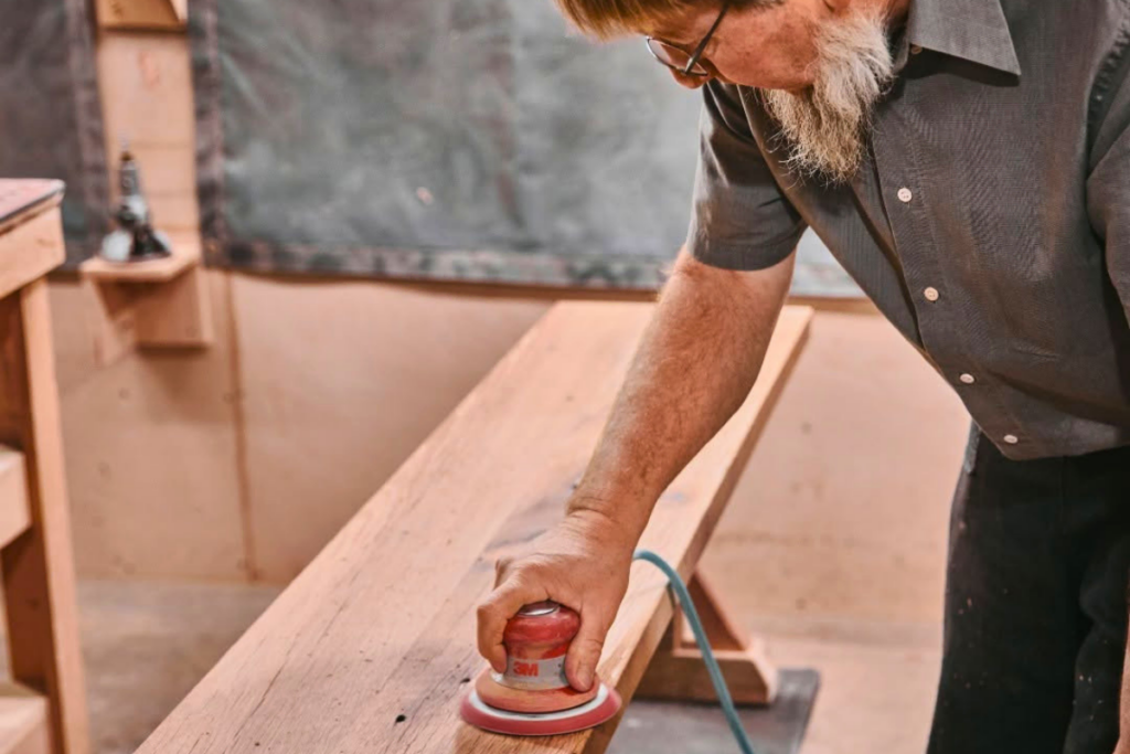 Amish man sanding a piece of wood